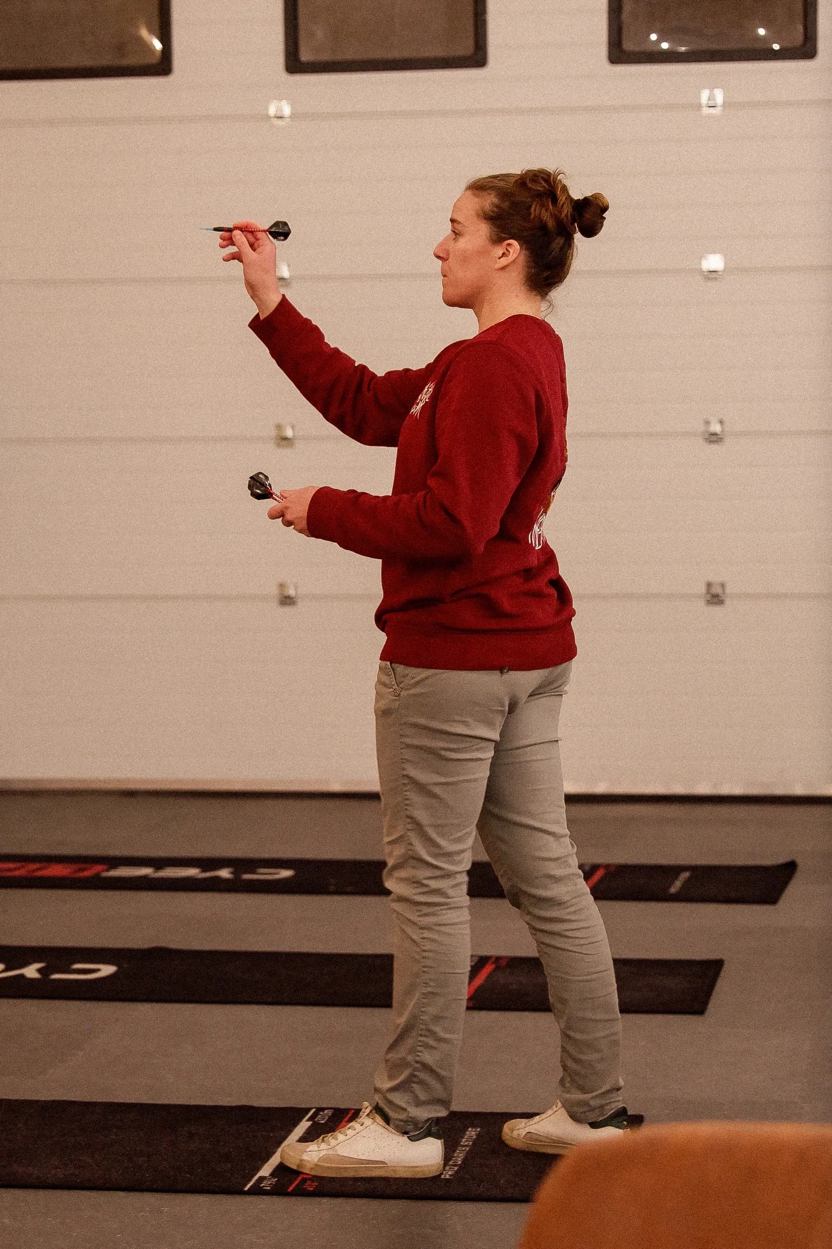Joueuse en plein lancer de fléchette devant les cibles connectées.